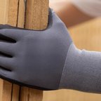 Grey PU-coated glove gripping a parcel edge on a bench